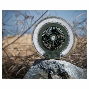 A Portable Disc Fan and Light with USB charging port placed on top of a rock.