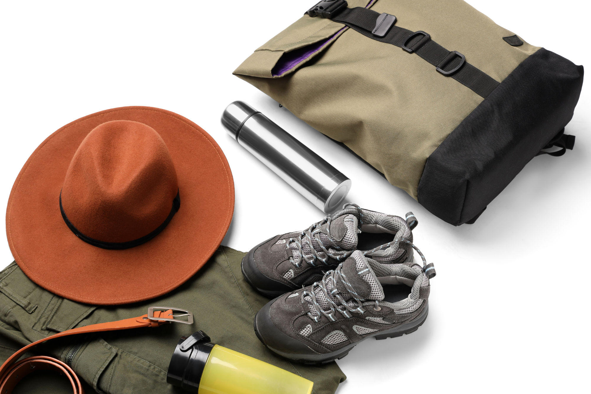 An Array Of Hiking Gear On A White Background, Suitable For Travelling Off-Grid, Including A Beige Backpack, Brown Hat, Hiking Boots, Green Pants, A Water Bottle, And Metal Thermos.